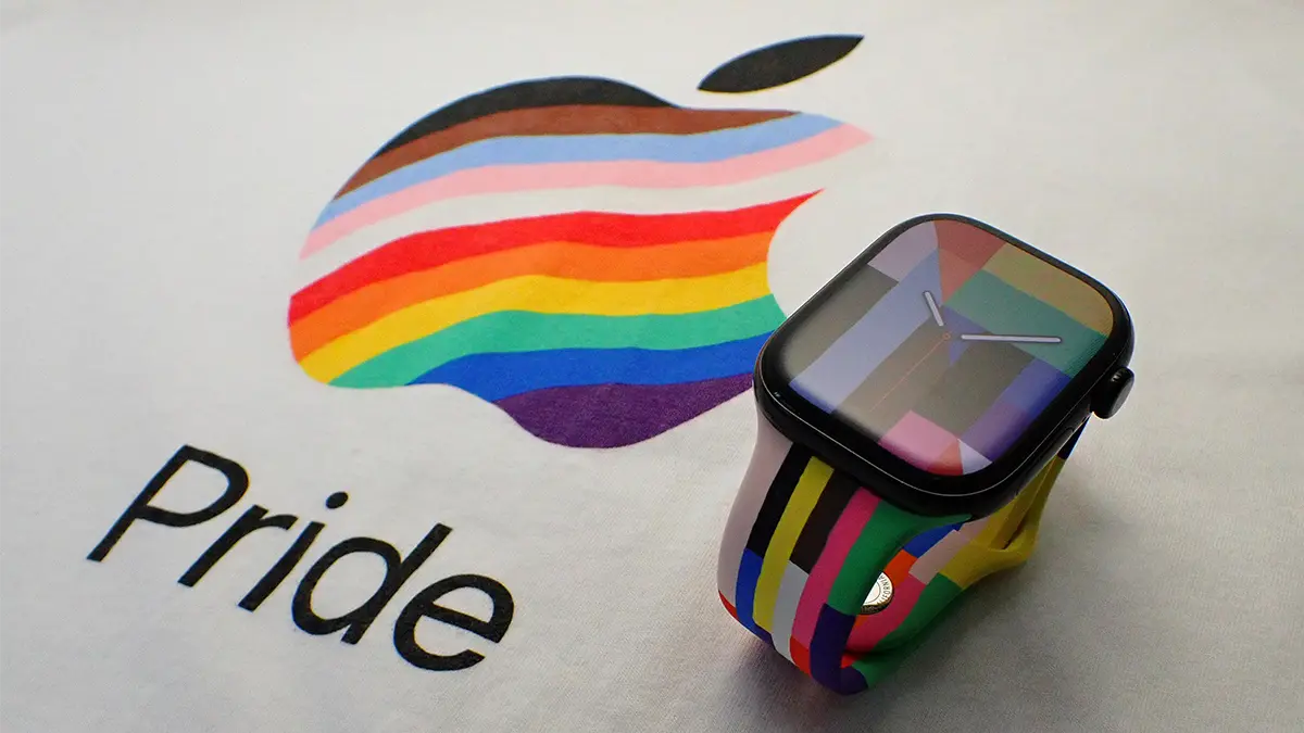 カラフルなプライドエディションスポーツバンドを取り付けたApple Watch。Appleの従業員むけプライドTシャツの上に置かれている。